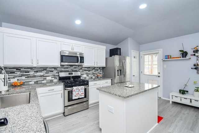 kitchen with stainless steel appliances, decorative backsplash, light wood-style floors, and white cabinetry