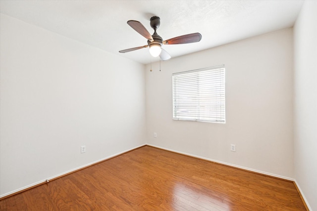 spare room with wood finished floors, a ceiling fan, and baseboards