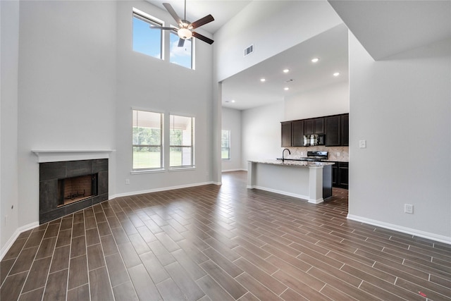 600 Barton Place Dr, Cleveland, TX 77327 - unfurnished living room with ceiling fan, a high ceiling, a tiled fireplace, dark wood-style floors, and recessed lighting