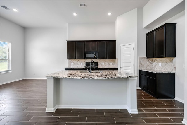 600 Barton Place Dr, Cleveland, TX 77327 - kitchen with black microwave, wood finish floors, backsplash, light stone countertops, and recessed lighting