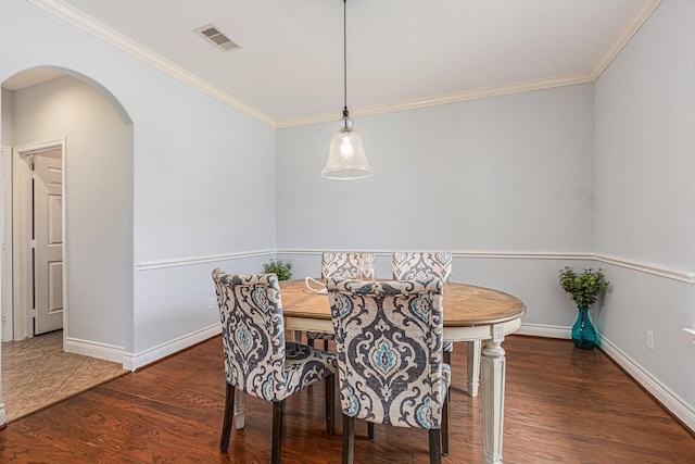dining room with arched walkways, visible vents, baseboards, wood finished floors, and crown molding