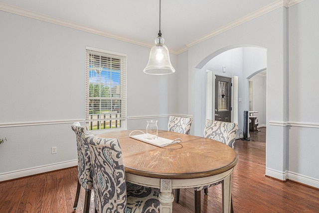dining area featuring baseboards, wood finished floors, arched walkways, and ornamental molding
