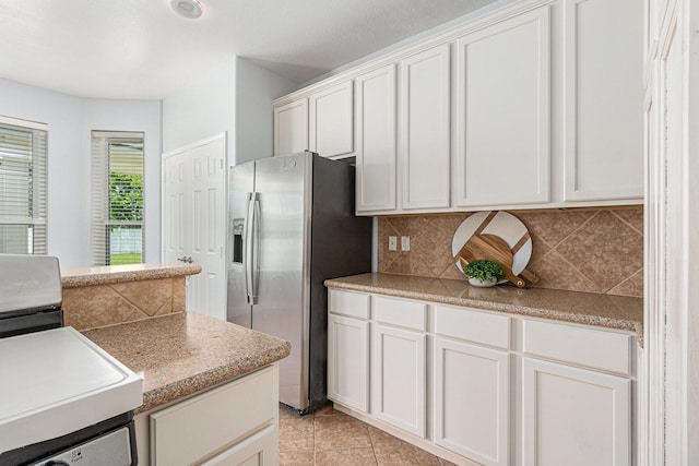 kitchen with white cabinets, tasteful backsplash, stainless steel refrigerator with ice dispenser, and light tile patterned floors