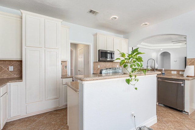 kitchen featuring arched walkways, appliances with stainless steel finishes, tasteful backsplash, and visible vents