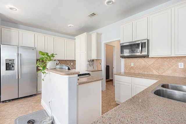 kitchen featuring a sink, light tile patterned flooring, stainless steel appliances, visible vents, and a kitchen island