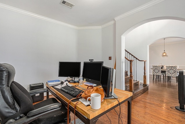 home office with arched walkways, ornamental molding, wood finished floors, and visible vents