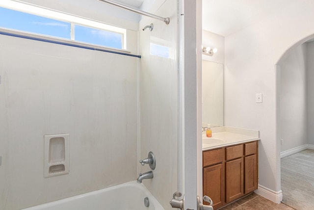 bathroom with baseboards, vanity, and tub / shower combination