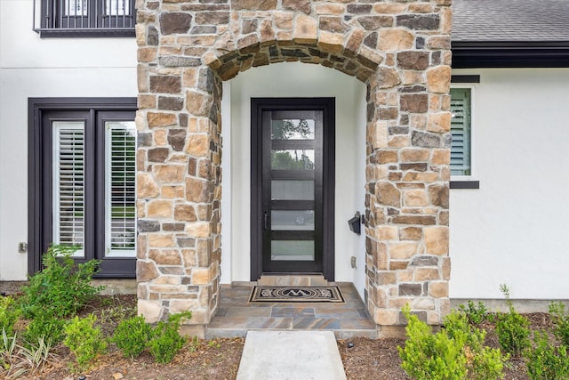 doorway to property featuring stone siding and stucco siding