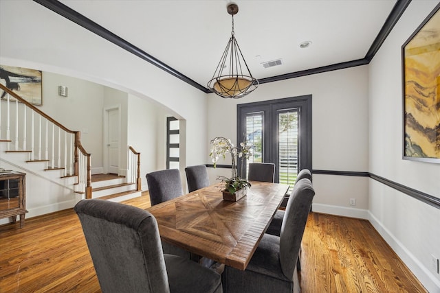 dining room with arched walkways, stairway, visible vents, and crown molding