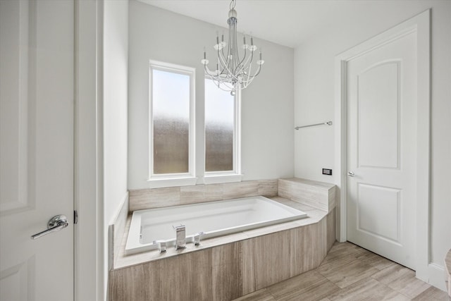 bathroom with a garden tub and a chandelier