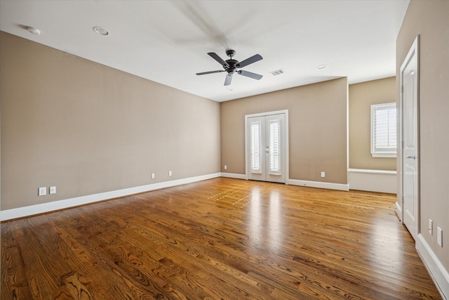 unfurnished room featuring baseboards, wood finished floors, visible vents, and ceiling fan