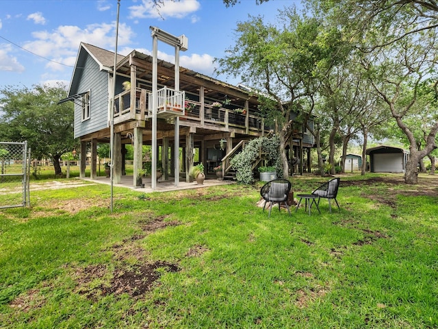 back of property with a lawn, a detached carport, stairs, and a wooden deck