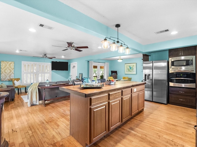 kitchen featuring visible vents, stainless steel appliances, light wood finished floors, and a kitchen island