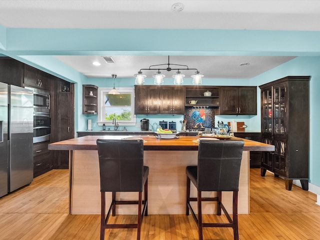 kitchen featuring appliances with stainless steel finishes, butcher block counters, open shelves, and a sink
