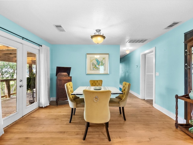 dining space with light wood-type flooring, visible vents, french doors, and baseboards