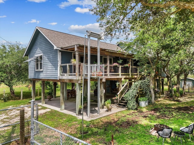 rear view of house featuring a wooden deck, stairway, a carport, roof with shingles, and fence