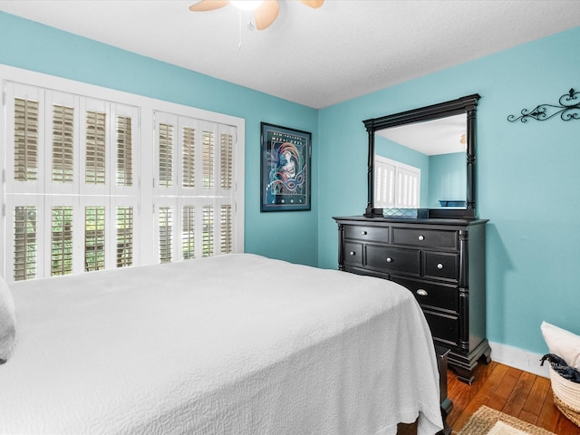 bedroom featuring dark wood-style floors, a ceiling fan, multiple windows, and baseboards