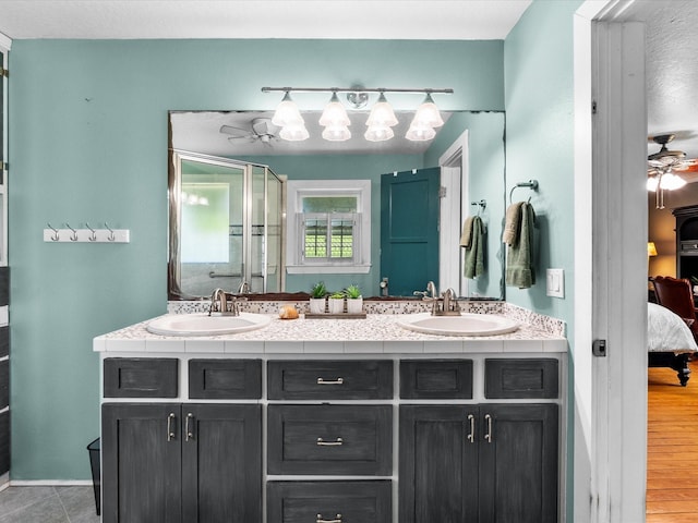ensuite bathroom with a ceiling fan, connected bathroom, double vanity, and a sink