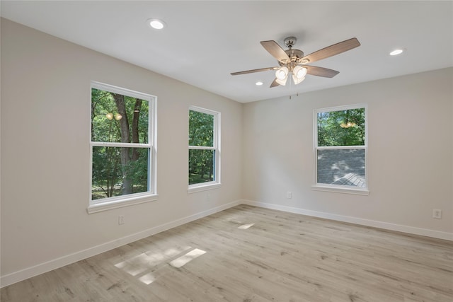 spare room with plenty of natural light, baseboards, and light wood-type flooring