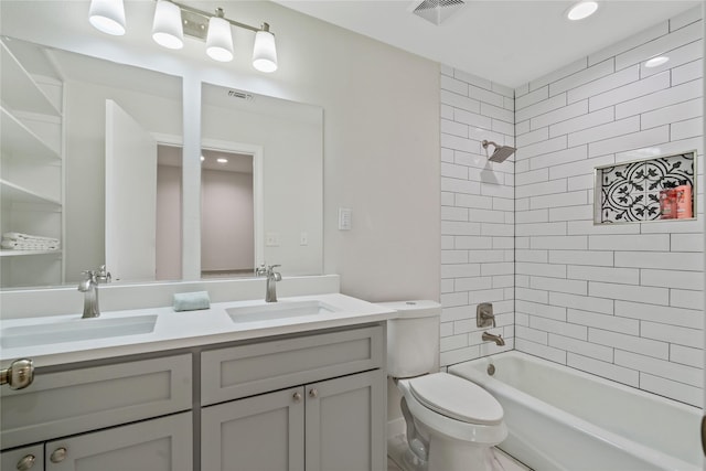 full bath with visible vents, a sink, double vanity, and toilet