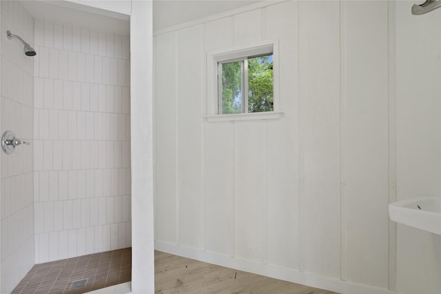 full bathroom with a tile shower and wood finished floors