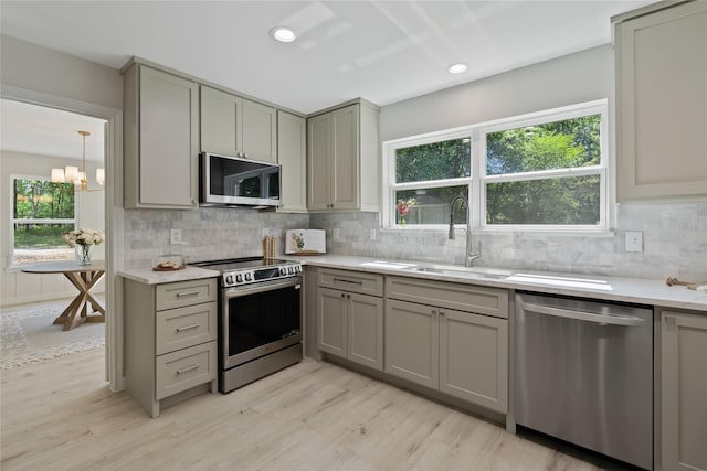 kitchen featuring a sink, light wood-style flooring, gray cabinetry, and stainless steel appliances