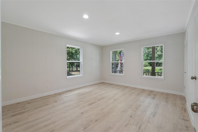 empty room featuring light wood-type flooring, ornamental molding, baseboards, and recessed lighting