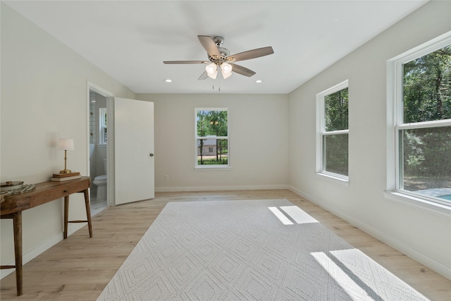 empty room with baseboards, a wealth of natural light, and light wood finished floors