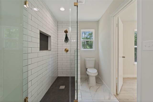full bath featuring toilet, baseboards, a tile shower, and marble finish floor