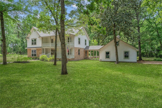 rear view of property featuring brick siding, a lawn, a balcony, and a porch