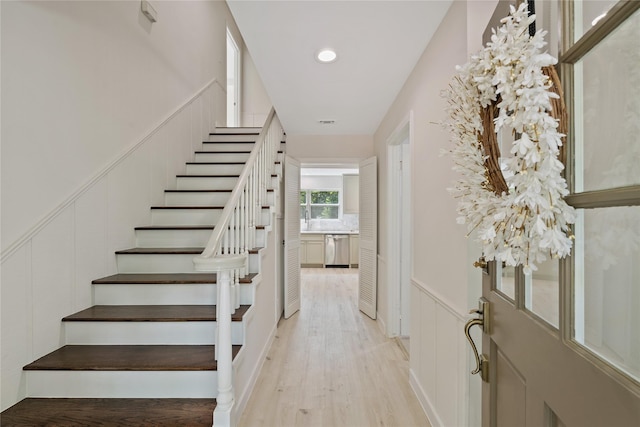 stairway featuring visible vents, wainscoting, wood finished floors, a decorative wall, and recessed lighting