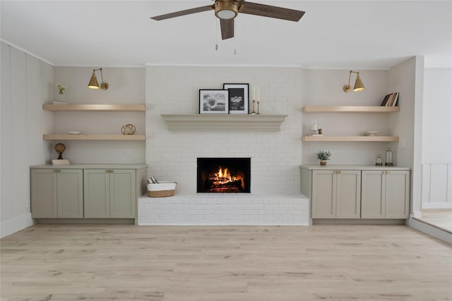 living area featuring light wood-type flooring, a brick fireplace, crown molding, and ceiling fan