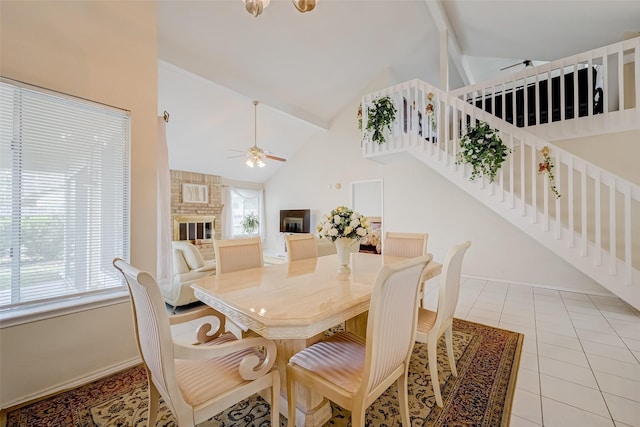 dining space with beam ceiling, baseboards, high vaulted ceiling, a ceiling fan, and a fireplace