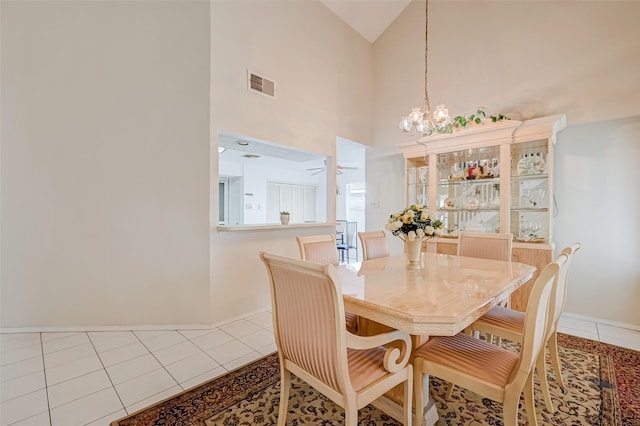 dining space featuring tile patterned floors, baseboards, visible vents, ceiling fan with notable chandelier, and high vaulted ceiling