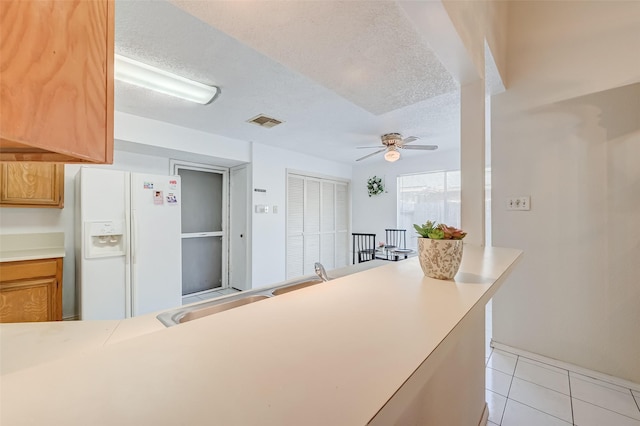 kitchen featuring light countertops, visible vents, a ceiling fan, white fridge with ice dispenser, and a textured ceiling