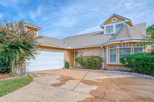 view of front of home with brick siding, an attached garage, driveway, and a shingled roof