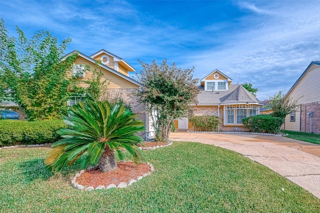 view of front of property with brick siding, driveway, and a front lawn