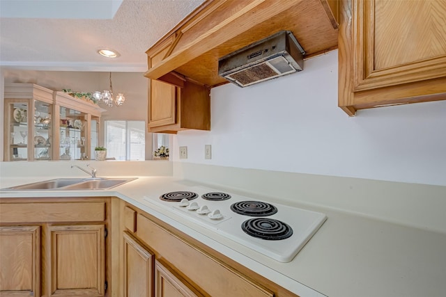 kitchen featuring ventilation hood, white electric cooktop, light countertops, a sink, and a notable chandelier