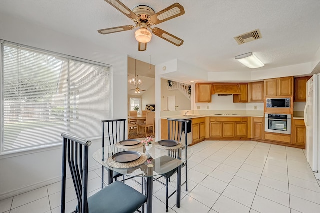 dining room with light tile patterned flooring, visible vents, and ceiling fan with notable chandelier