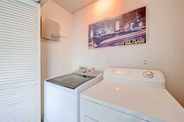 washroom featuring a textured ceiling, washing machine and clothes dryer, and laundry area