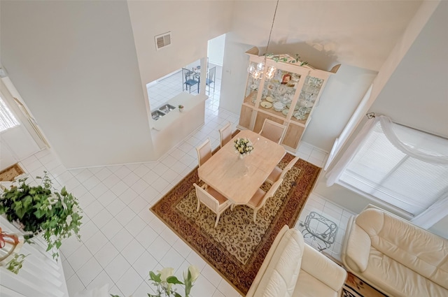 tiled living area with a baseboard heating unit, a towering ceiling, and visible vents
