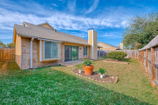 rear view of house featuring stone siding, a lawn, a fenced backyard, and a patio