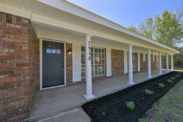 property entrance featuring brick siding and a porch