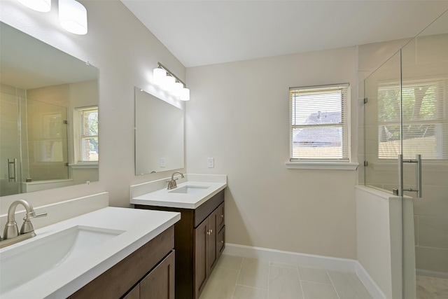 full bathroom featuring two vanities, baseboards, a stall shower, and a sink