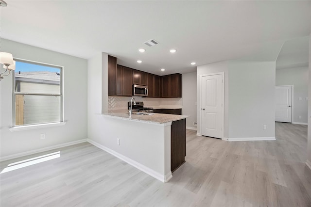 810 Clear Valley Ln, Dayton, TX 77535 - kitchen featuring stainless steel appliances, light wood finished floors, dark brown cabinets, recessed lighting, and a peninsula
