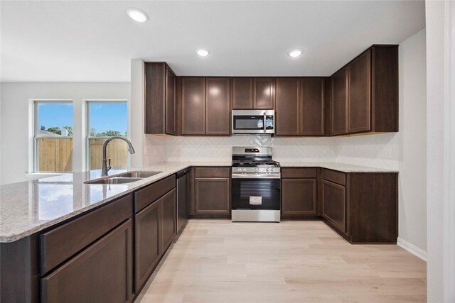 810 Clear Valley Ln, Dayton, TX 77535 - kitchen featuring stainless steel appliances, a peninsula, light wood finished floors, light stone counters, and backsplash