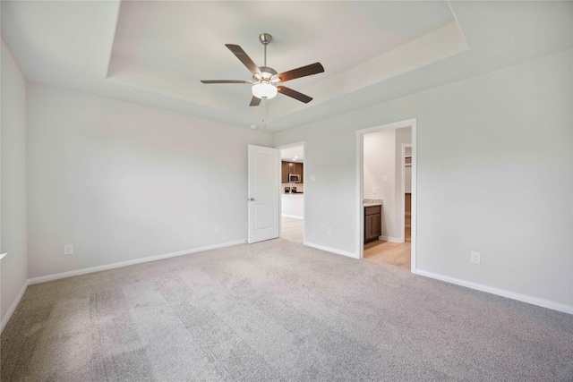 810 Clear Valley Ln, Dayton, TX 77535 - unfurnished bedroom with a tray ceiling, light carpet, ensuite bathroom, and ceiling fan