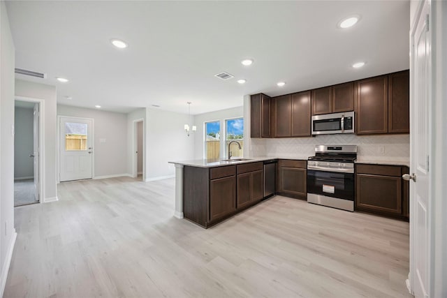 810 Clear Valley Ln, Dayton, TX 77535 - kitchen with stainless steel appliances, a peninsula, decorative backsplash, light wood-style flooring, and recessed lighting