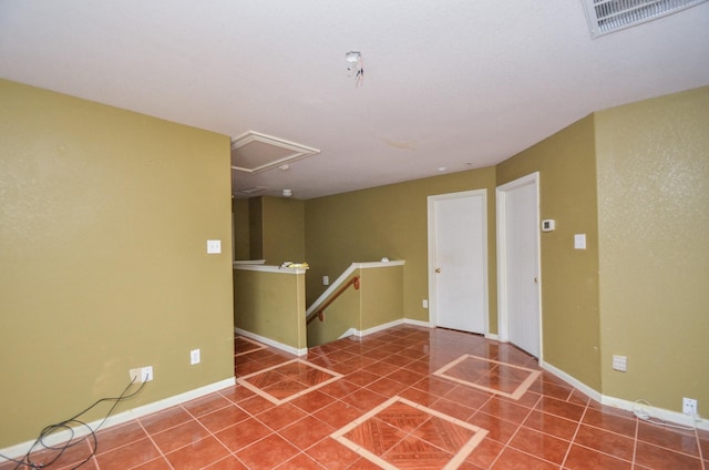 tiled spare room with attic access, baseboards, and visible vents