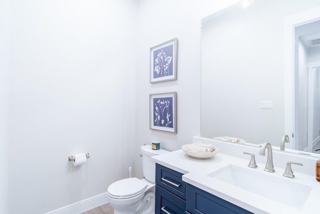 bathroom with toilet, vanity, and baseboards